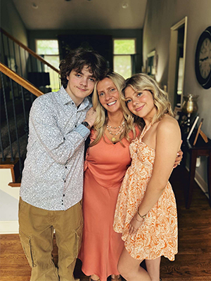 Three individuals standing in a home, smiling at the camera.